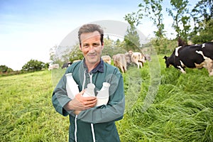 Happy farmer with bottles of freshly collected cow milk