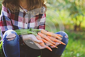 Happy farmer child girl picking fresh home growth carrot harvest from own garden