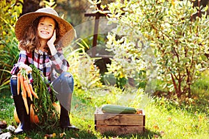 Happy farmer child girl sitting with autumn harvest in the garden