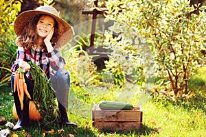 Happy farmer child girl sitting with autumn harvest in the garden