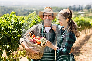 Happy farmer couple holding a basket of vegetables
