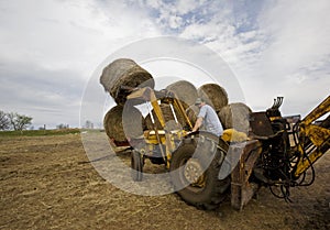 Happy Farmer on Tractor with Round Hay Bales