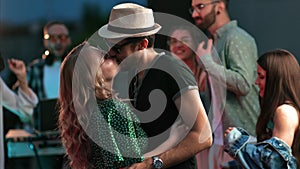 Happy fashion couple dancing at roof party night discotheque surrounded by people crowd