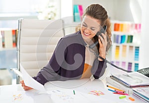 Happy fashion designer in office talking phone