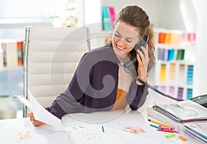 Šťastný móda návrhár v kancelária hovorenie telefón 