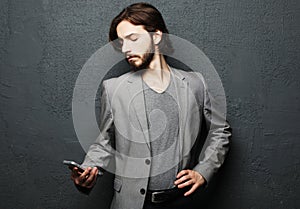 Happy fashion man typing sms on gray background