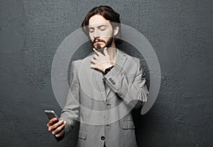 Happy fashion man typing sms on gray background