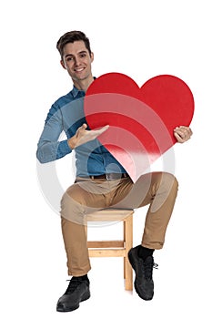 Happy fashion model holding big red heart and smiling