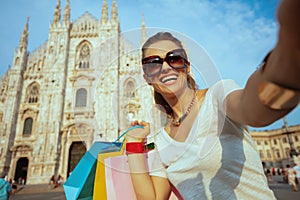 Happy fashion-monger with colorful shopping bags taking selfie