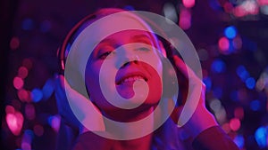 Happy fashionable blonde woman dancing in a nightclub. A young woman moves rhythmically to music on headphones.