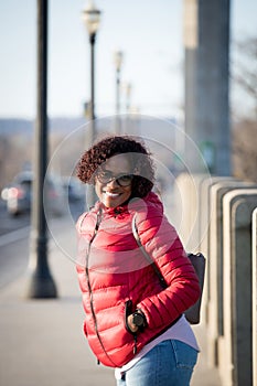 Happy fashionable woman along the city streets in red jacket