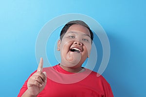 Happy fat Asian boy pointing finger up, having idea gesture