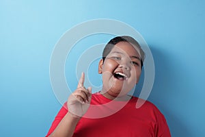 Happy fat Asian boy pointing finger up, having idea gesture