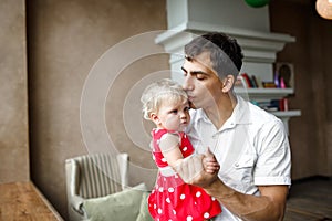 Happy father and 1 years old blonde daughter ,dad kisses baby in the temple