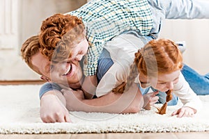 Happy father with adorable redhead children playing and having fun together on floor