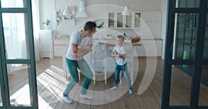 Happy father and adorable son synchronizing the dancing movements on the kitchen background. Happy family weekend