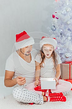 Happy Father and Baby with Christmas Gift near the Christmas Tree at home. Child opening a Gift Box