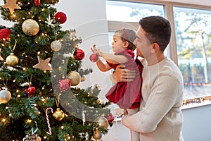 happy father and baby girl decorate christmas tree