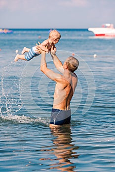 Happy father and baby having fun in the sea