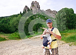 Happy father is carrying his baby in the knapsack.