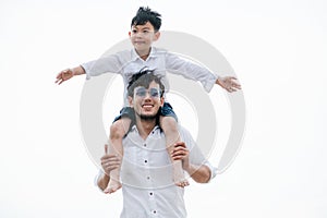 Happy father carrying his son on the neck.