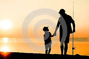 A Happy father and child fishermen catch fish by the sea on nature silhouette travel