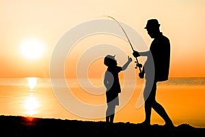 A Happy father and child fishermen catch fish by the sea on nature silhouette travel