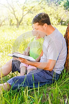 happy father with a child reading a book on the nature of the Bible