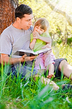 happy father with a child reading a book on the nature of the Bible