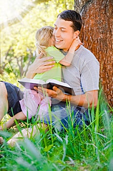 happy father with a child reading a book on the nature of the Bible