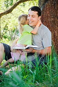 A happy father with a child reading a book on the nature of the Bible