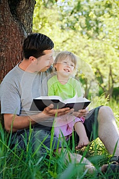 happy father with a child reading a book on the nature of the Bible