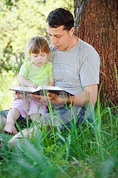 happy father with a child reading a book on the nature of the Bible