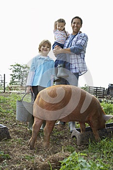 Happy Father And Children With Pig In Sty