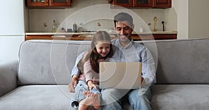 Happy father and cute little daughter girl watching funny movie