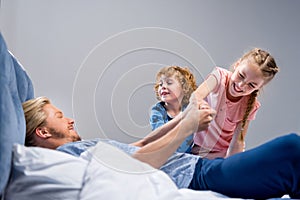 happy father with cute little kids having fun together in bed