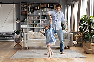 Happy father dancing with adorable little daughter, holding hands