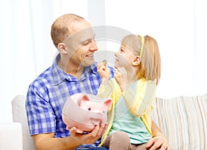 Happy father and daughter with big piggy bank