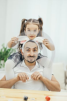 Happy father and daughter having fun together, daughter with cute pigtails is sitting on father`s shoulders, playing