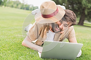 happy father and daughter hugging while using laptop on lawn