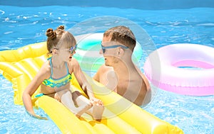 Happy father and daughter with inflatable mattress in swimming pool