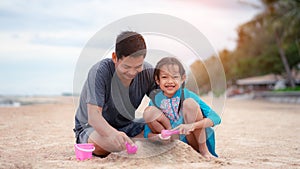 Happy father and daughter are making sand piles on the beach.Concept of fathers day