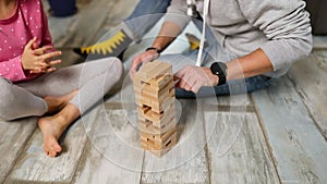 Happy father and daughter play game with wooden tower blocks bricks