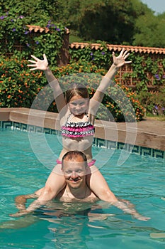 Happy father and daughter playing in a outdoor pool