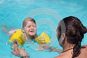 Happy father and daughter playing in the swimming pool; summertime background