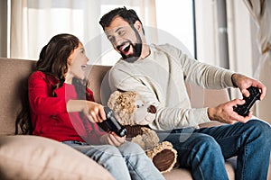 happy father and daughter playing video game at home and looking