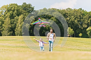 happy father and daughter running on meadow and playing