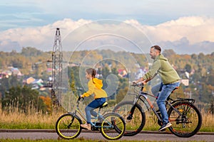 Happy father and daughter take bike ride in nature in autumn