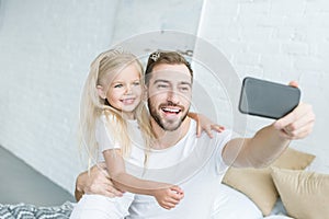 Happy father and daughter taking selfie with smartphone