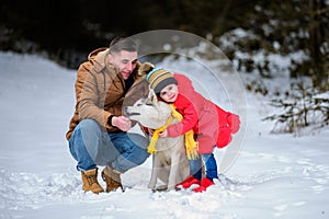 Happy father with daughter on a walk in the woods, girl and husky in yellow scarves, bright clothes in winter